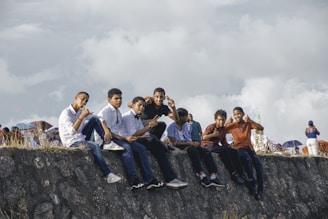 A group of people sitting on top of a stone wall