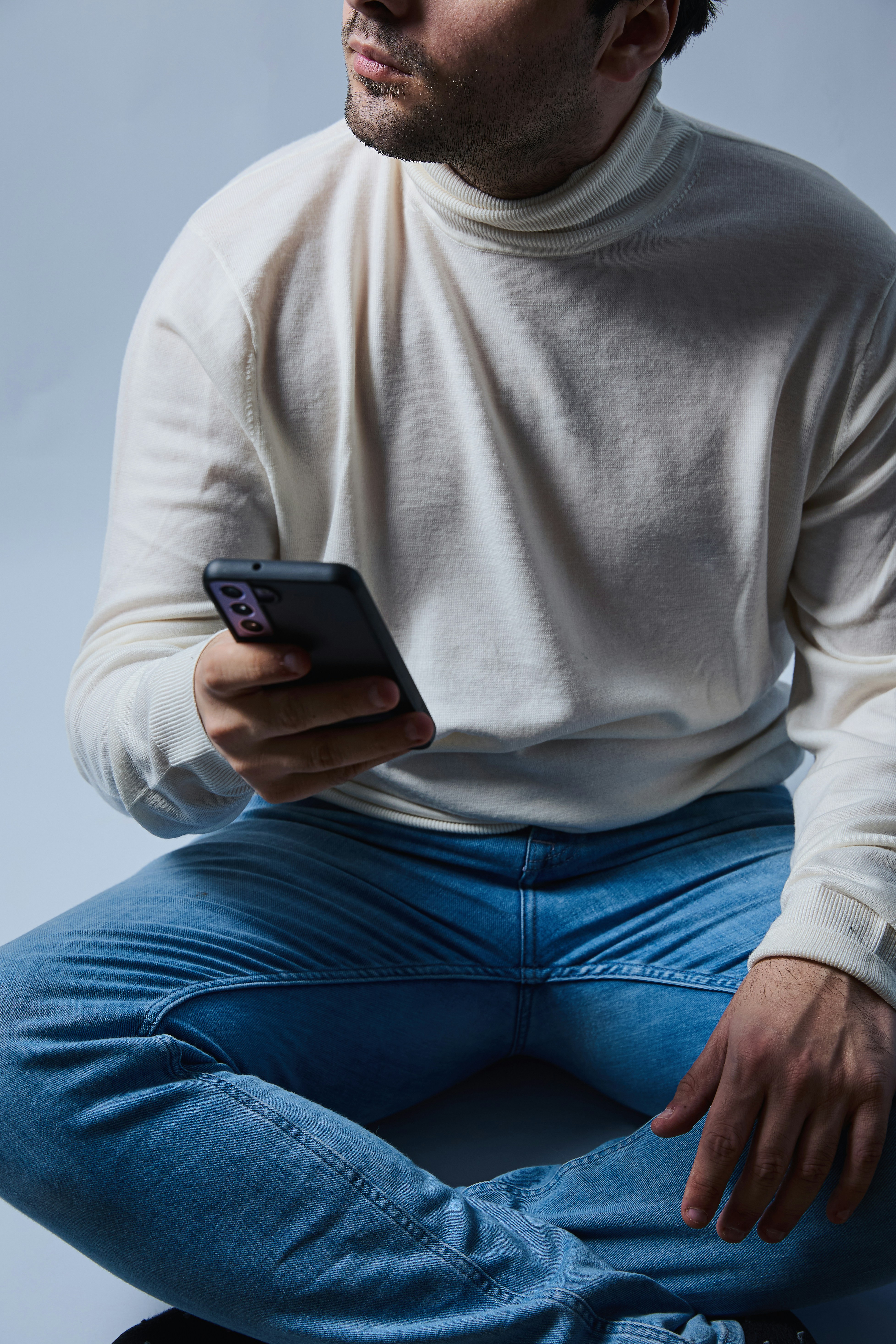 A man sitting on a skateboard holding a cell phone