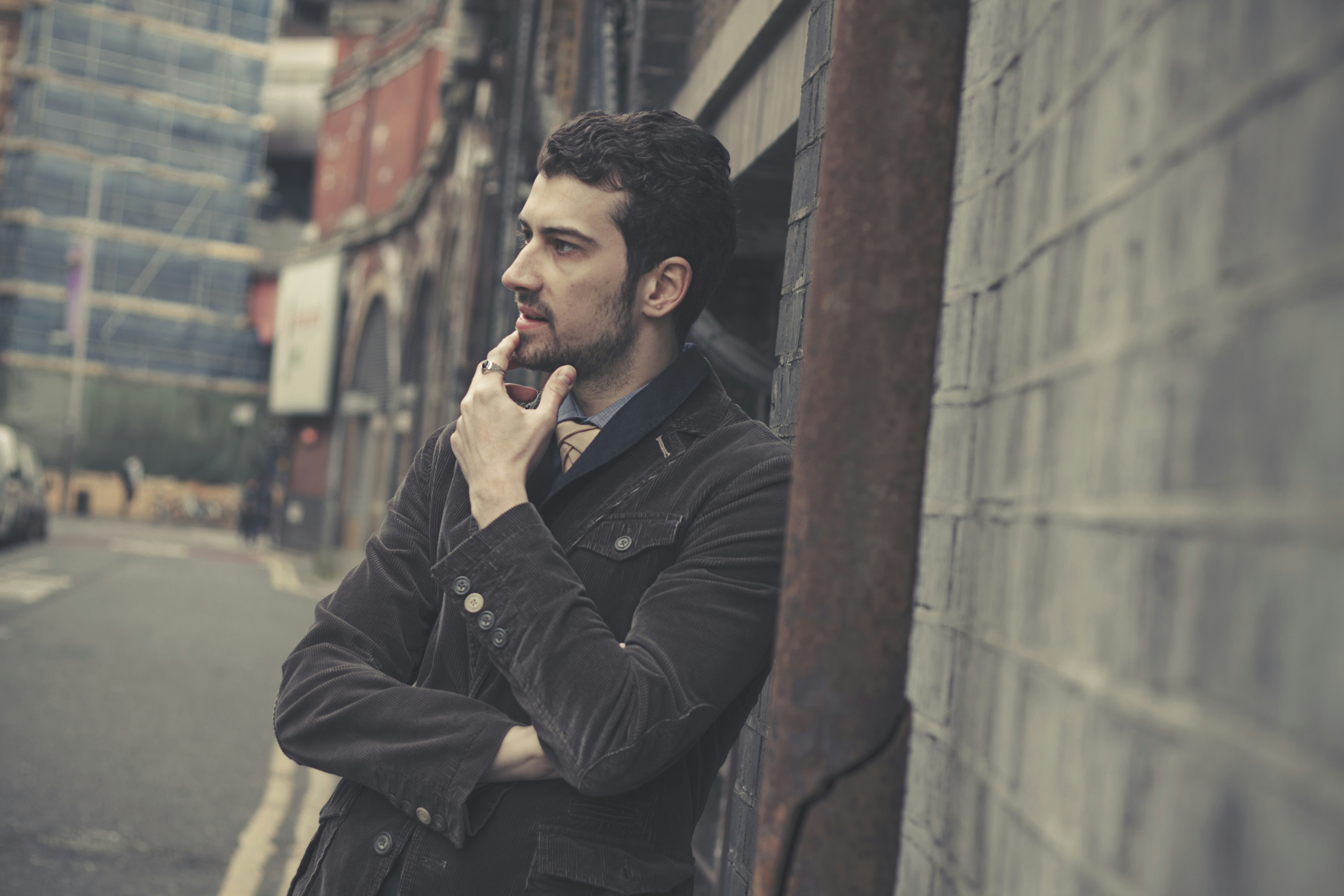 Ein Mann, der am Straßenrand an einer Mauer lehnt