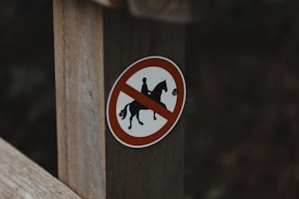 A no horse allowed sign on a wooden post