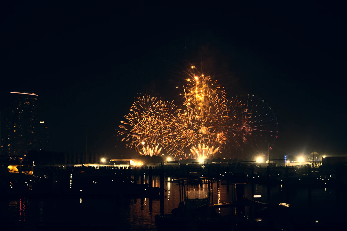 Fuegos artificiales iluminando el cielo nocturno sobre el agua durante una fiesta popular