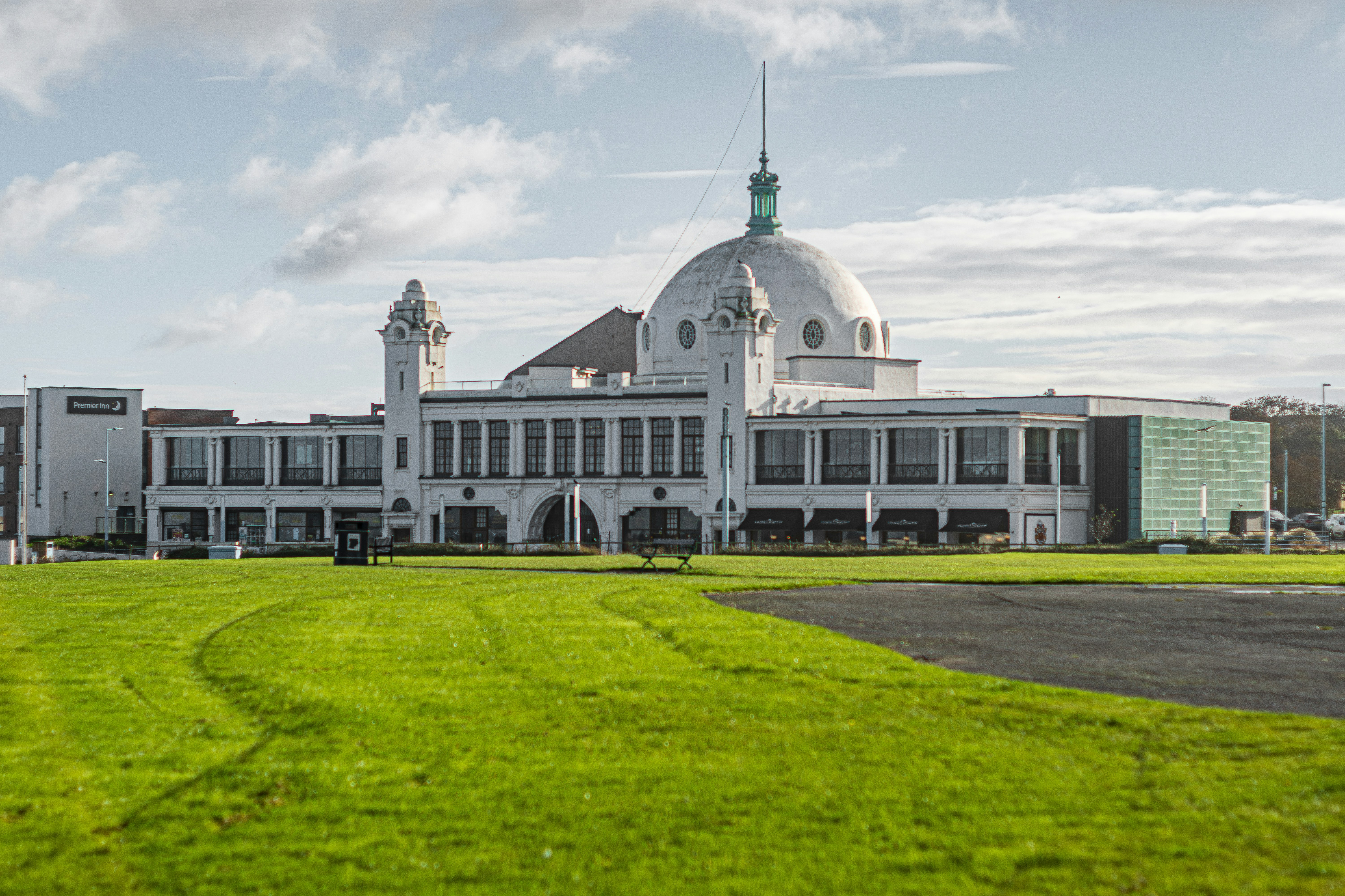 A large white building sitting on top of a lush green field photo ...