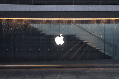 An apple logo is reflected in the glass of a building