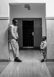 A man standing next to a little boy in a hallway