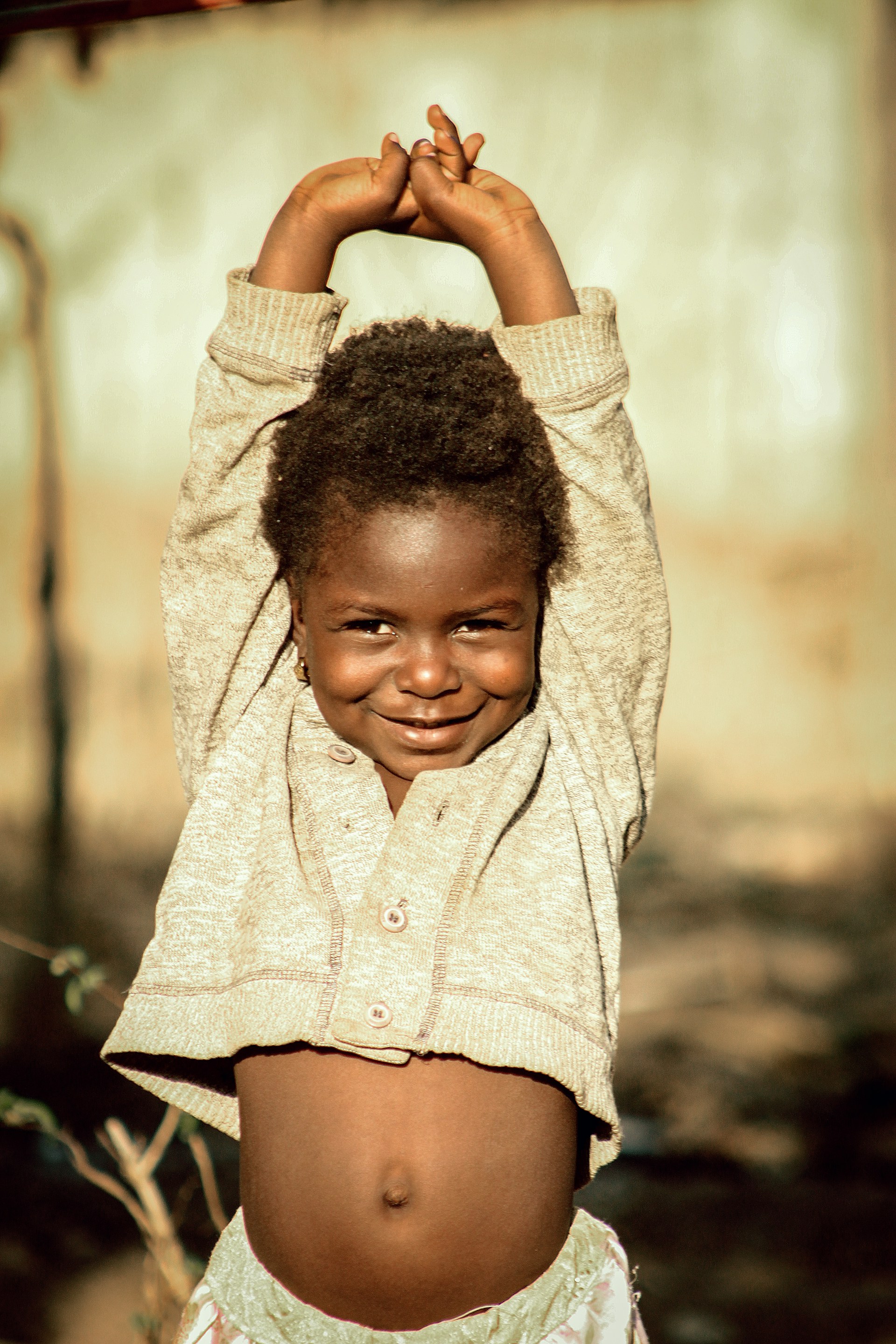 A little girl that is standing up with her hands on her head