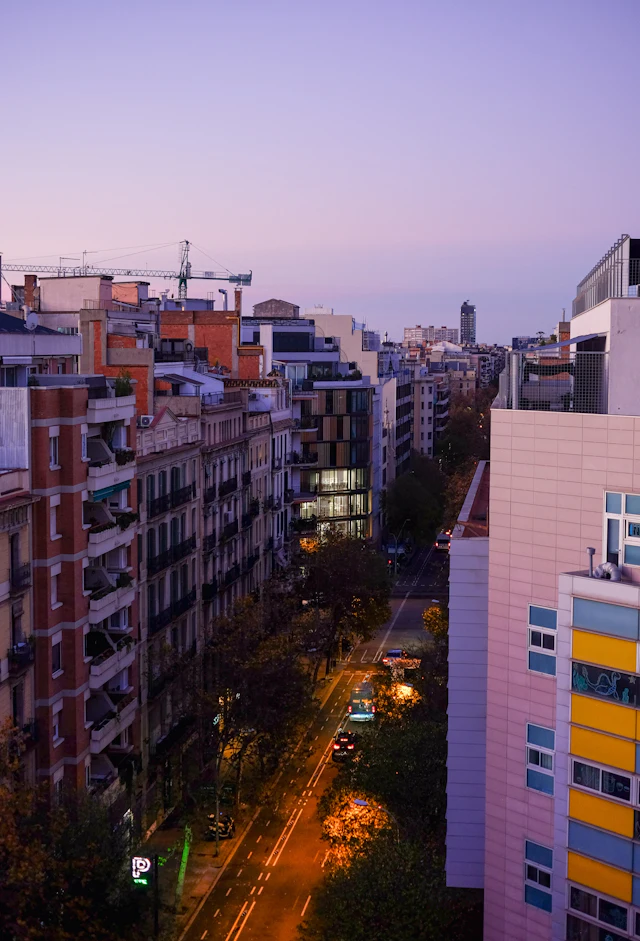 An elevated dusk view down a typical Eixample street lined with apartment blocks