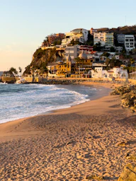A sandy beach with houses on a hill in the background
