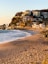 A sandy beach with houses on a hill in the background