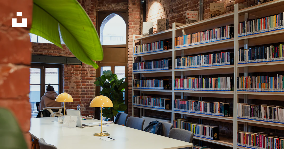 A library with a table and chairs and bookshelves photo – Free Human ...