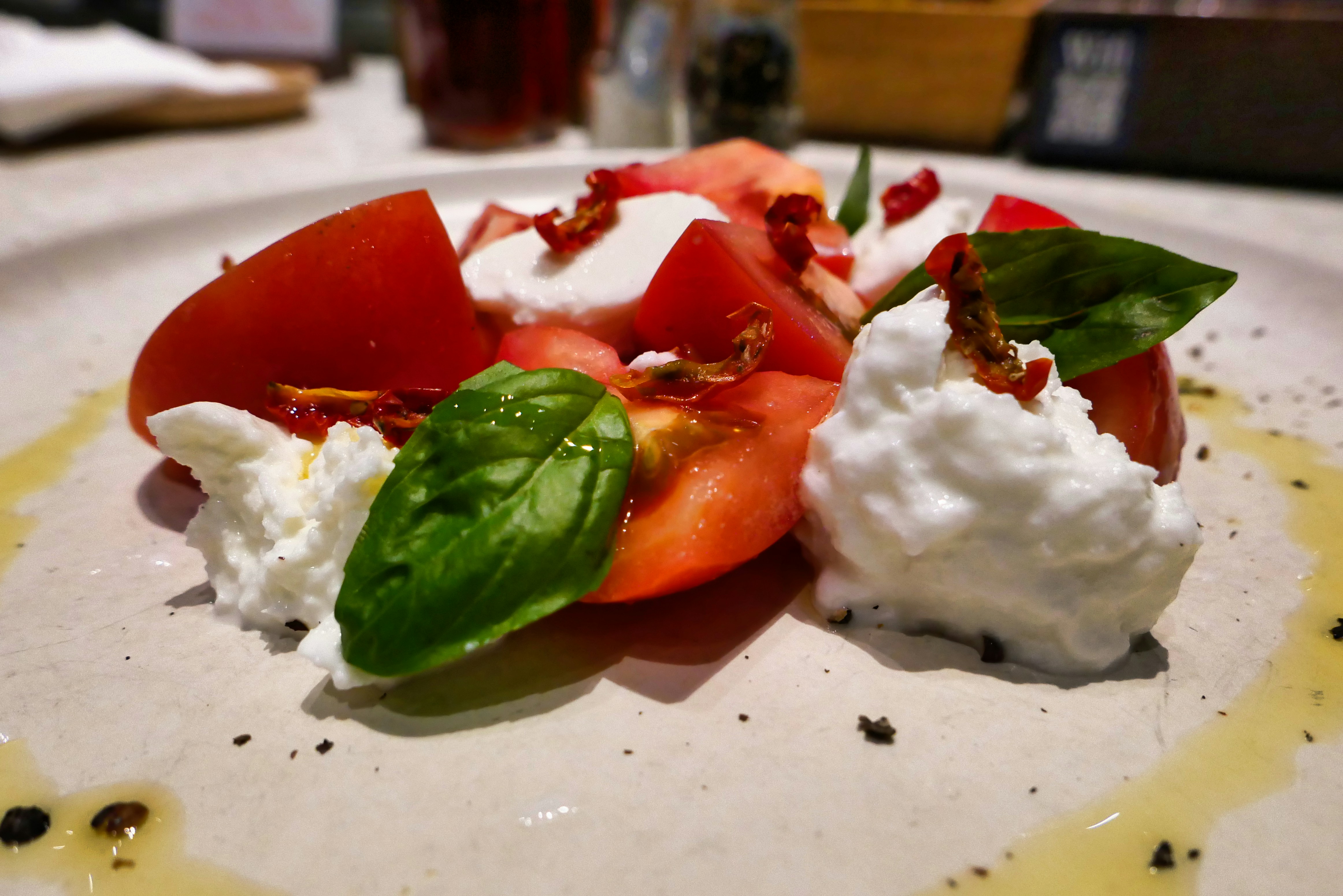 Une assiette blanche garnie de tomates tranchées et de crème fouettée