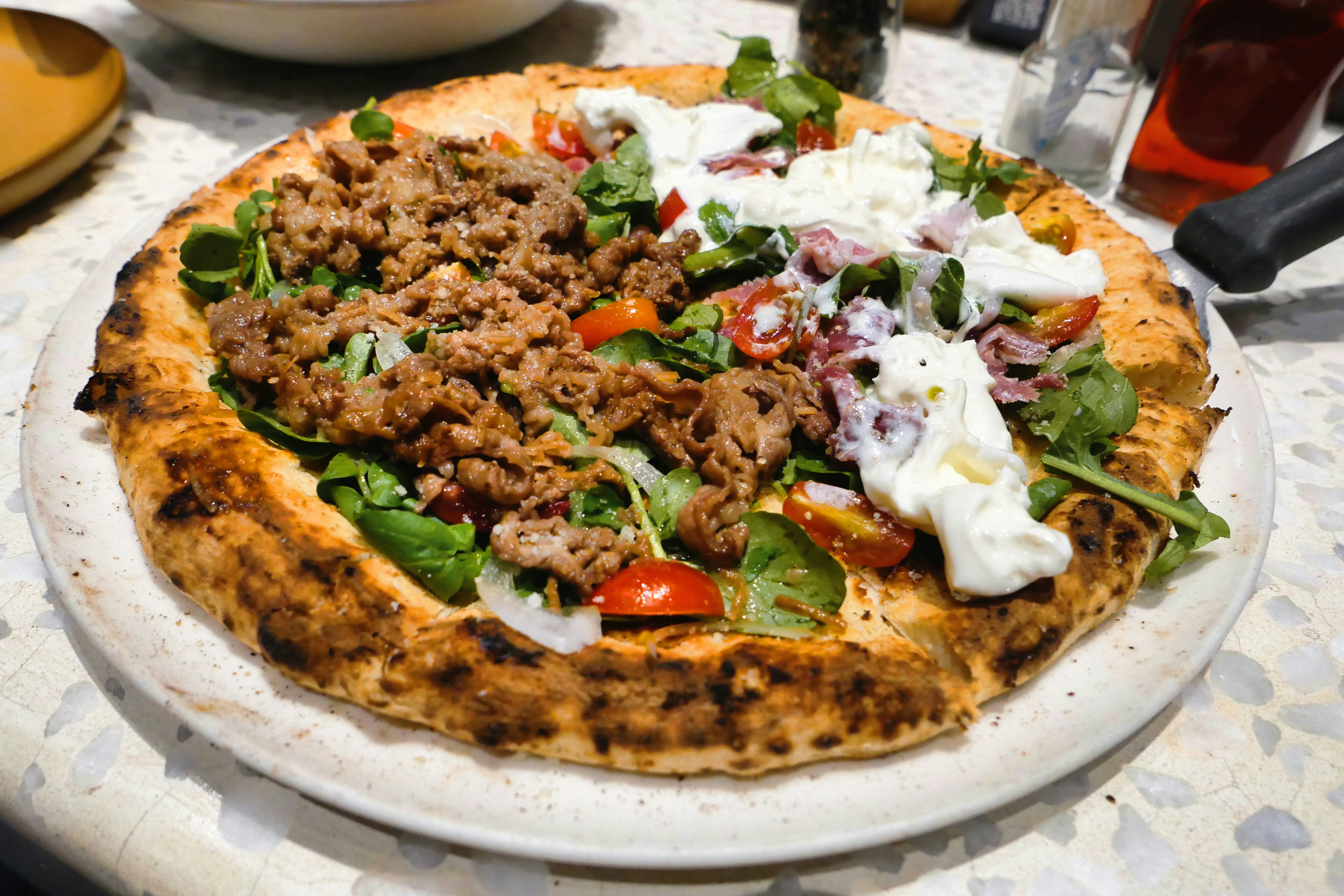 Une pizza avec de la viande et des légumes sur une assiette