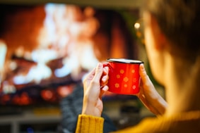 A woman holding a red cup in front of a television