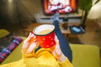 A woman holding a cup of coffee in front of a TV
