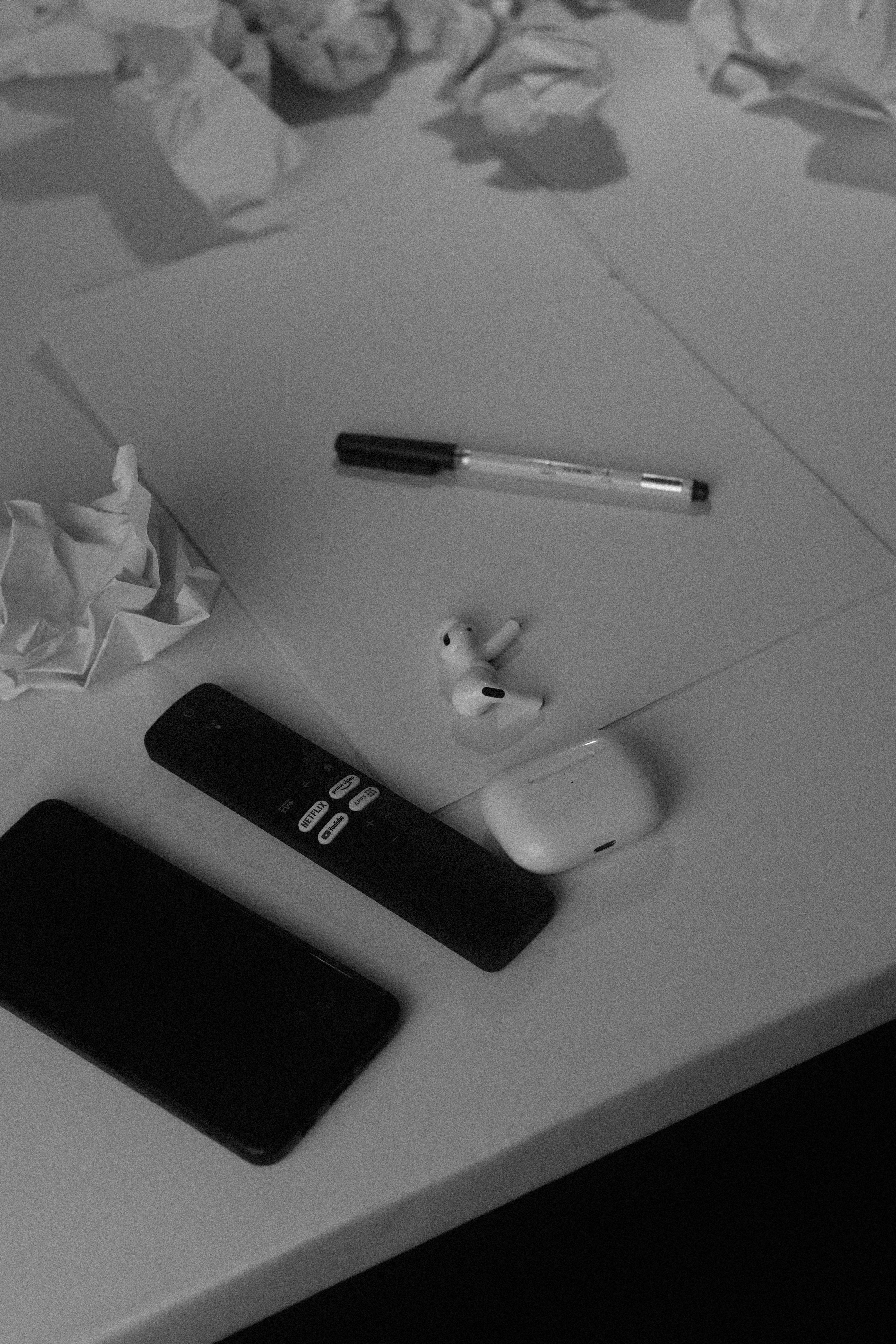 A desk with a cell phone, pen, and paper on it