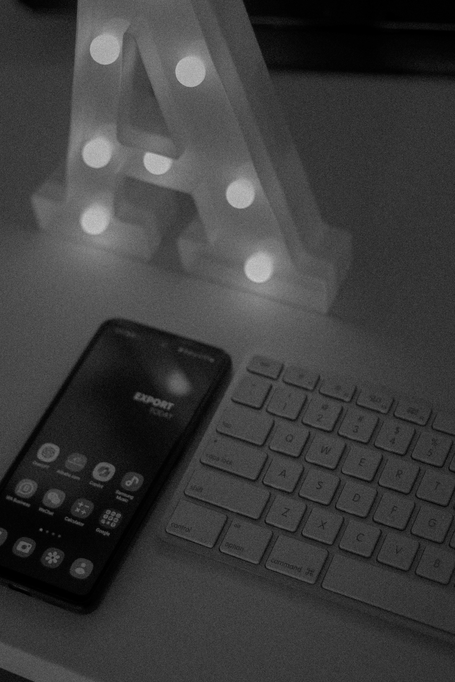 A cell phone sitting on top of a desk next to a keyboard