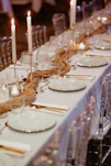 A long table is set with white plates and silverware