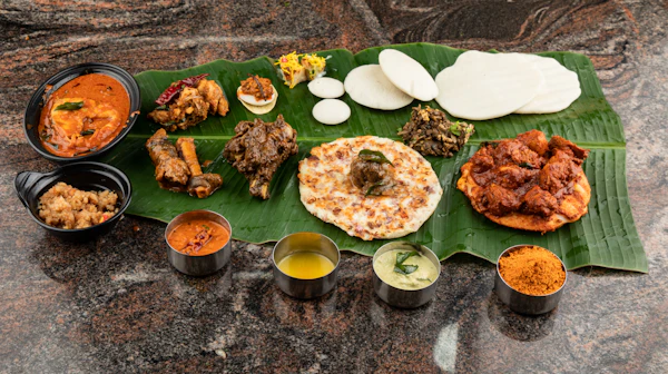 Coconut chutney, sambar and small coastal starters arranged on a banana leaf