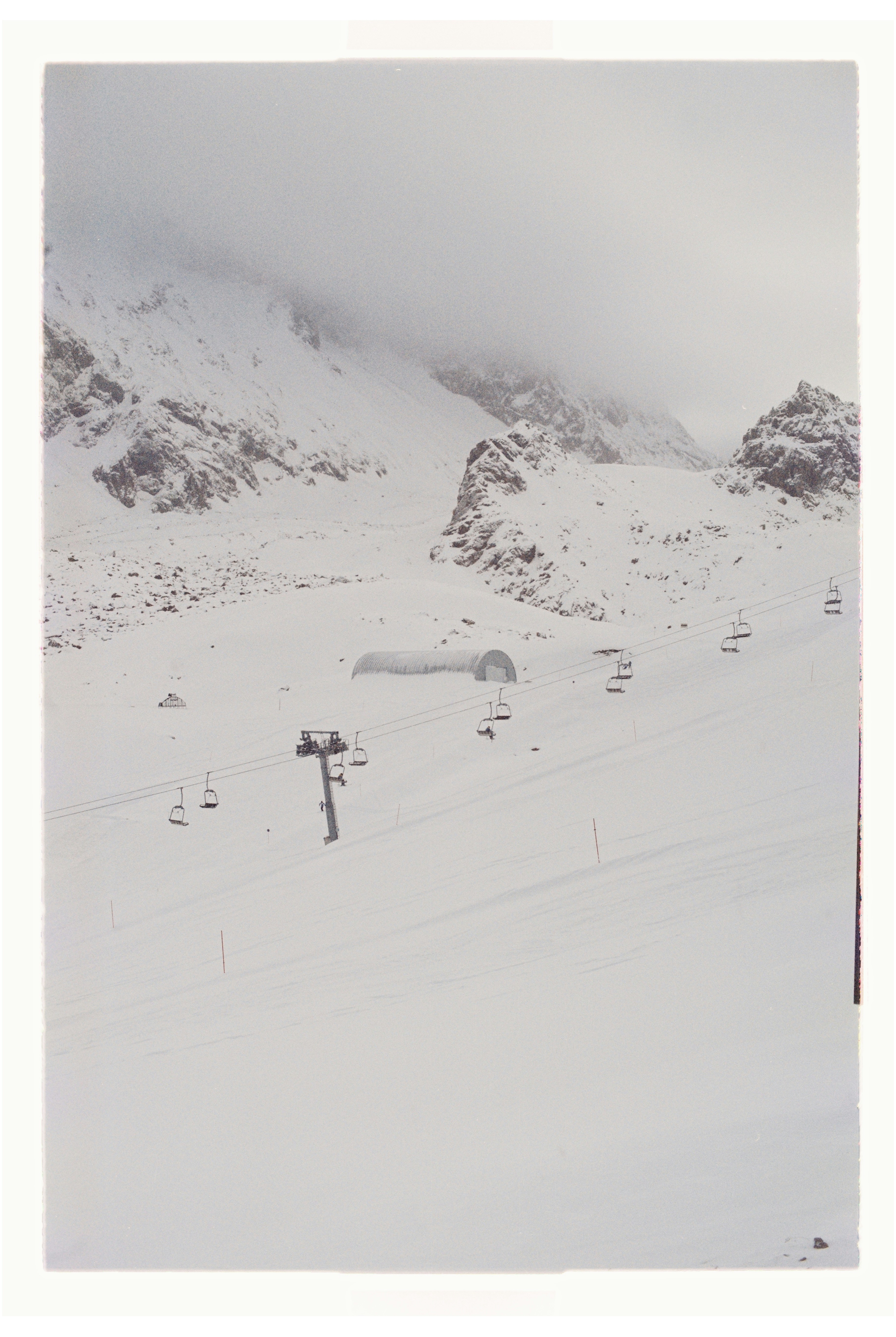 A snow covered mountain with a ski lift in the distance