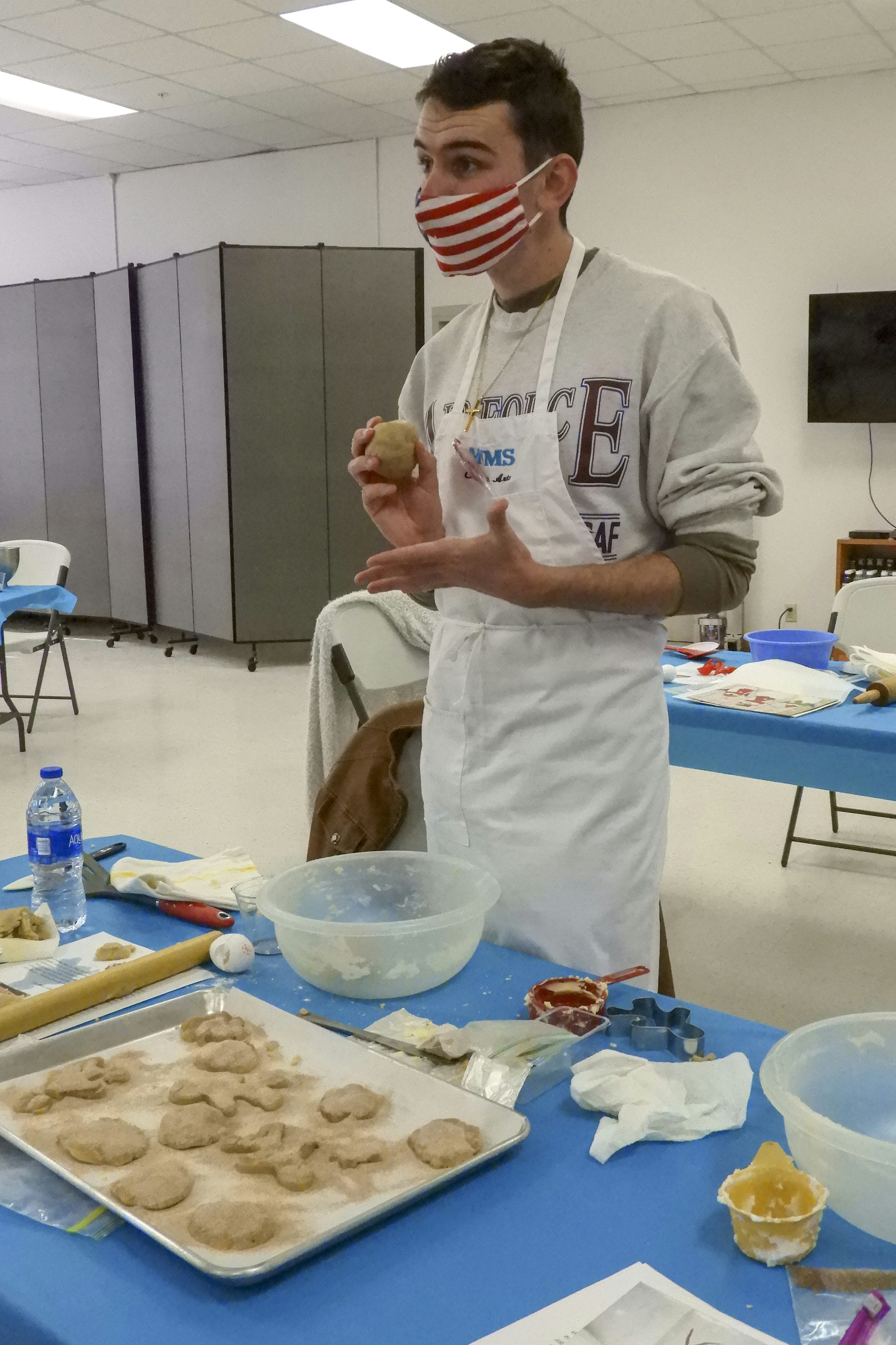 A man wearing a mask standing in front of a table filled with food