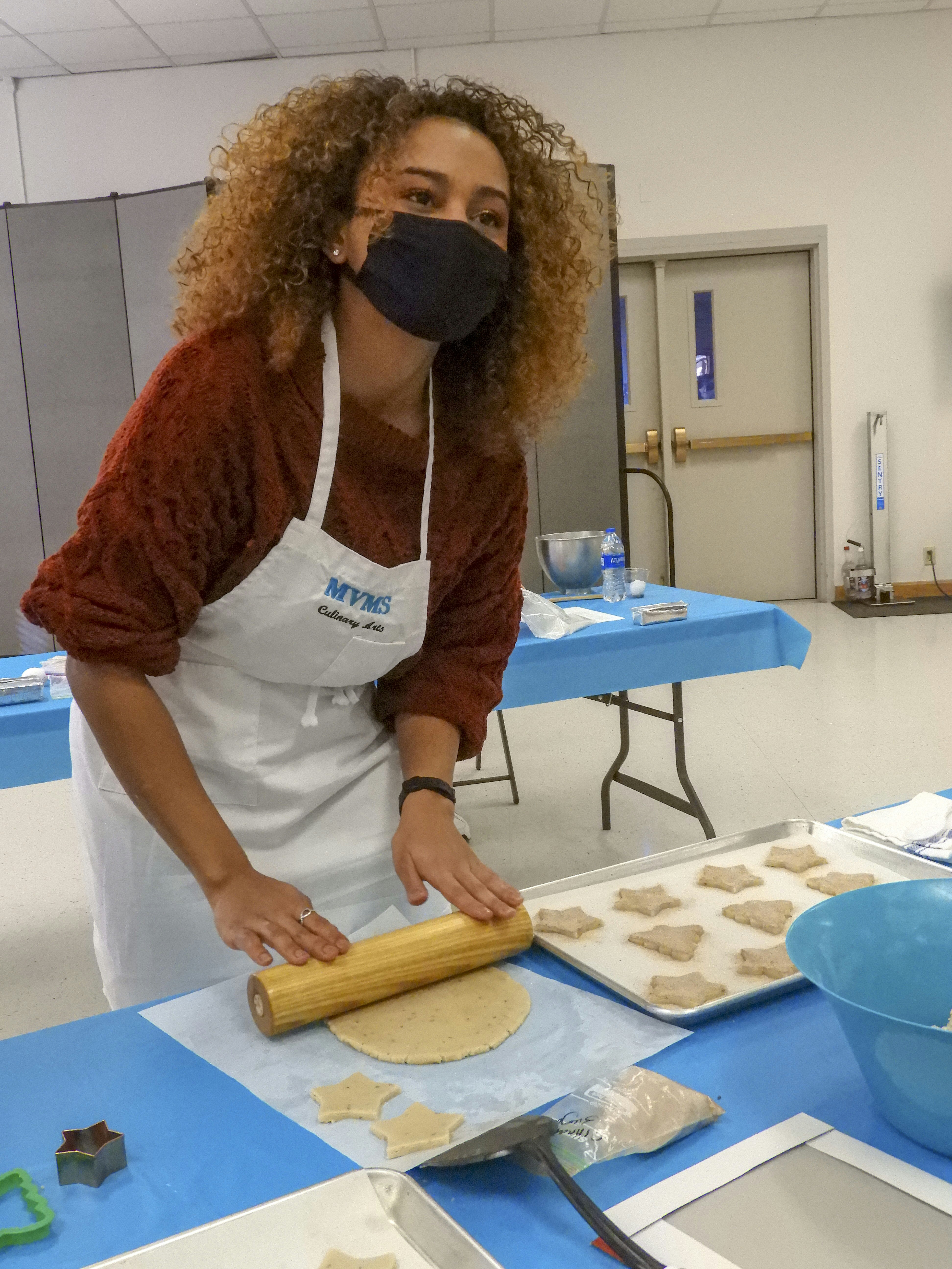 A woman wearing a face mask is making cookies