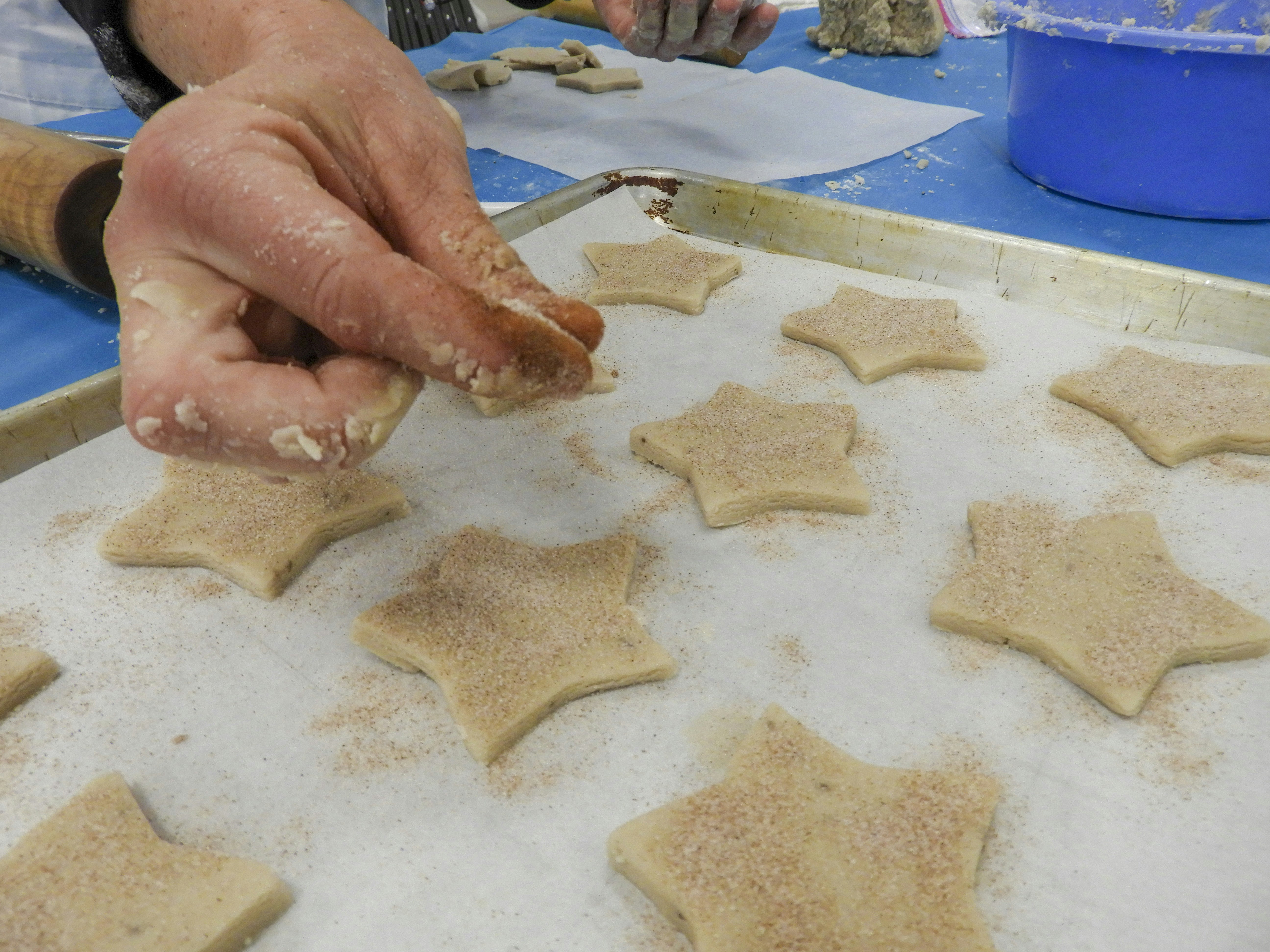 A person is making star shaped cookies on a cookie sheet