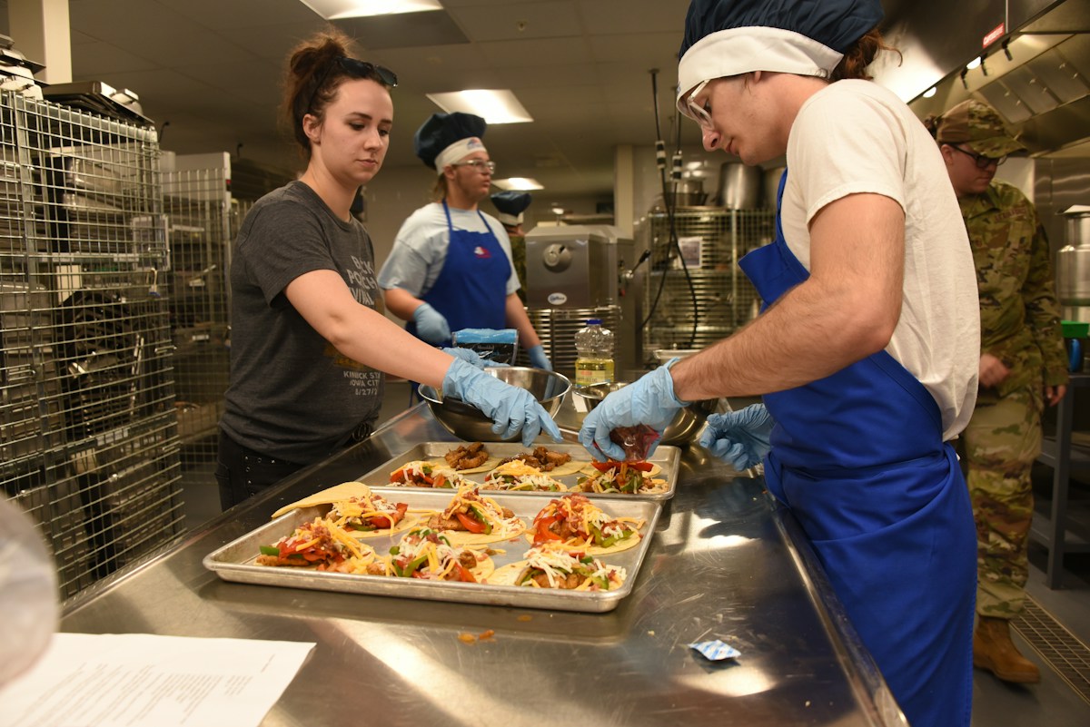 Volunteers in a school concession stand kitchen preparing food for a sports fundraiser event.