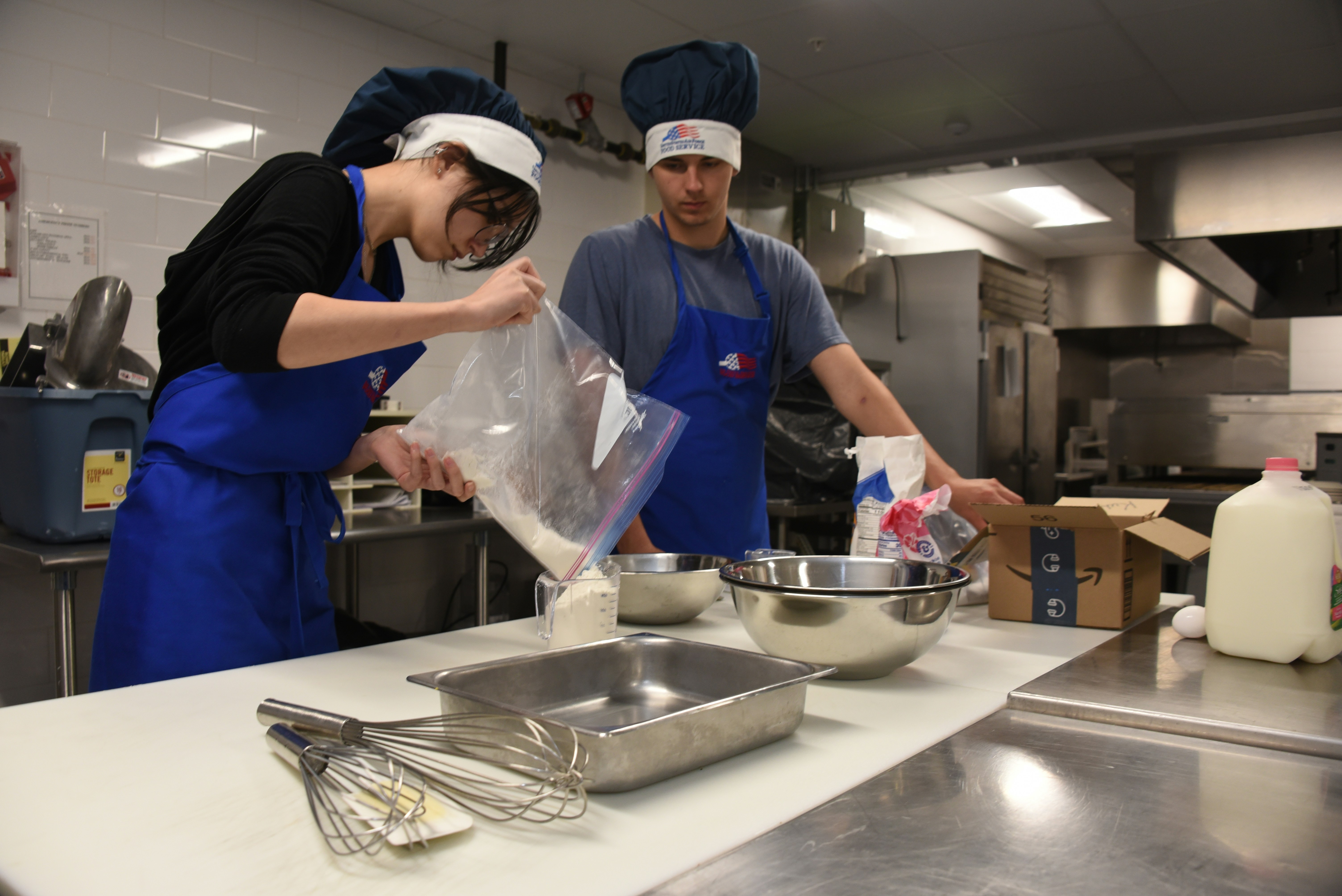 A couple of people in a kitchen preparing food