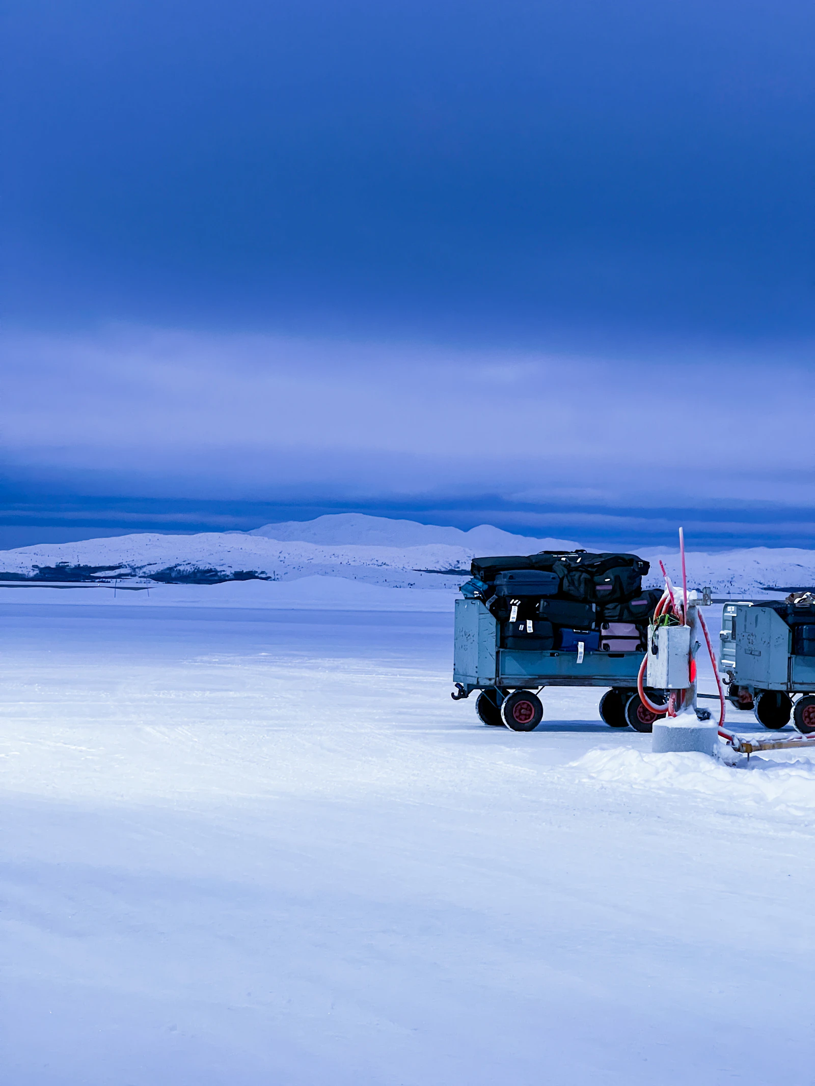 Deep blue winter twilight over snow-covered ground and low hills at Kirkenes, Norway