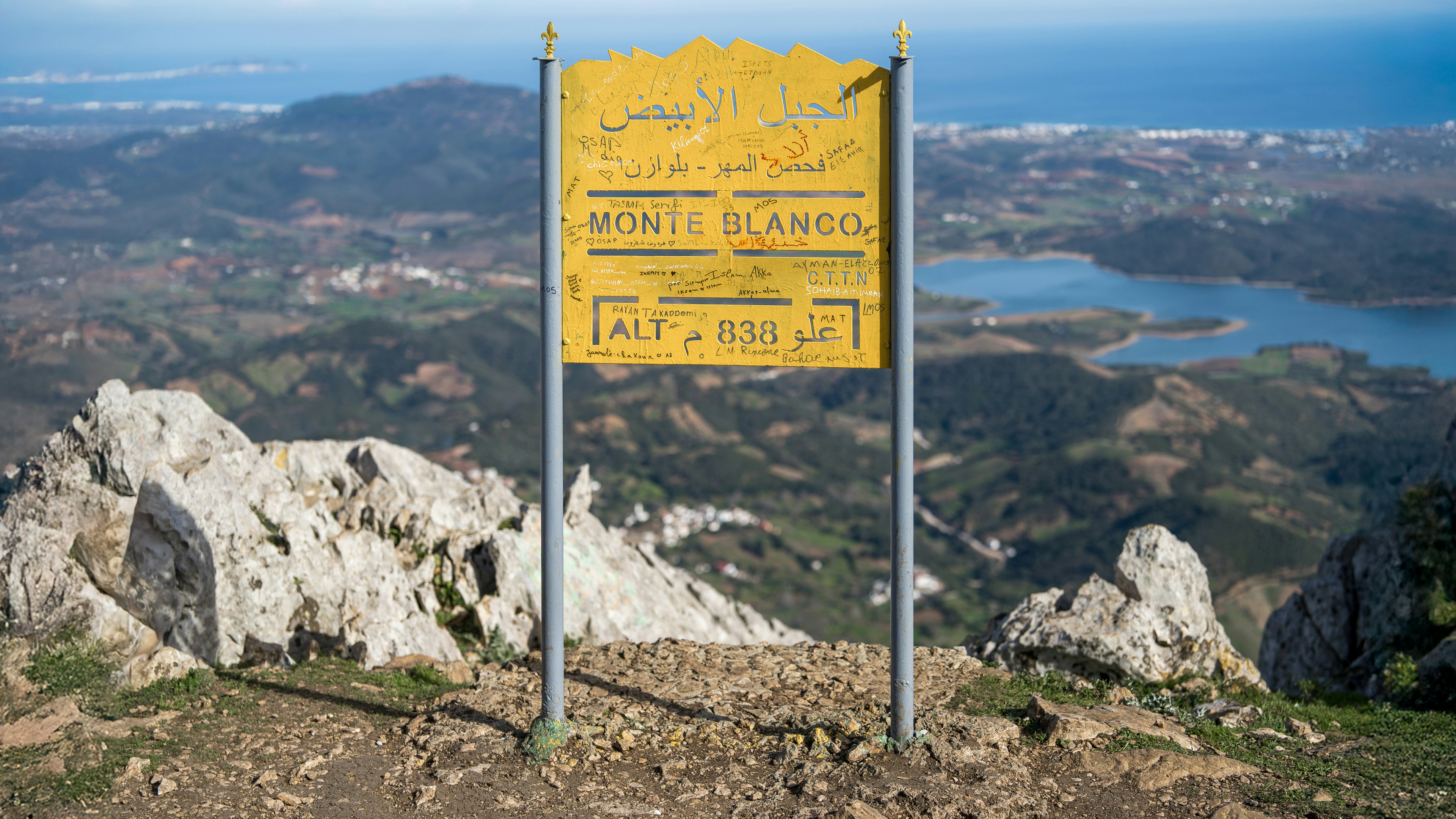 A yellow sign sitting on the side of a mountain