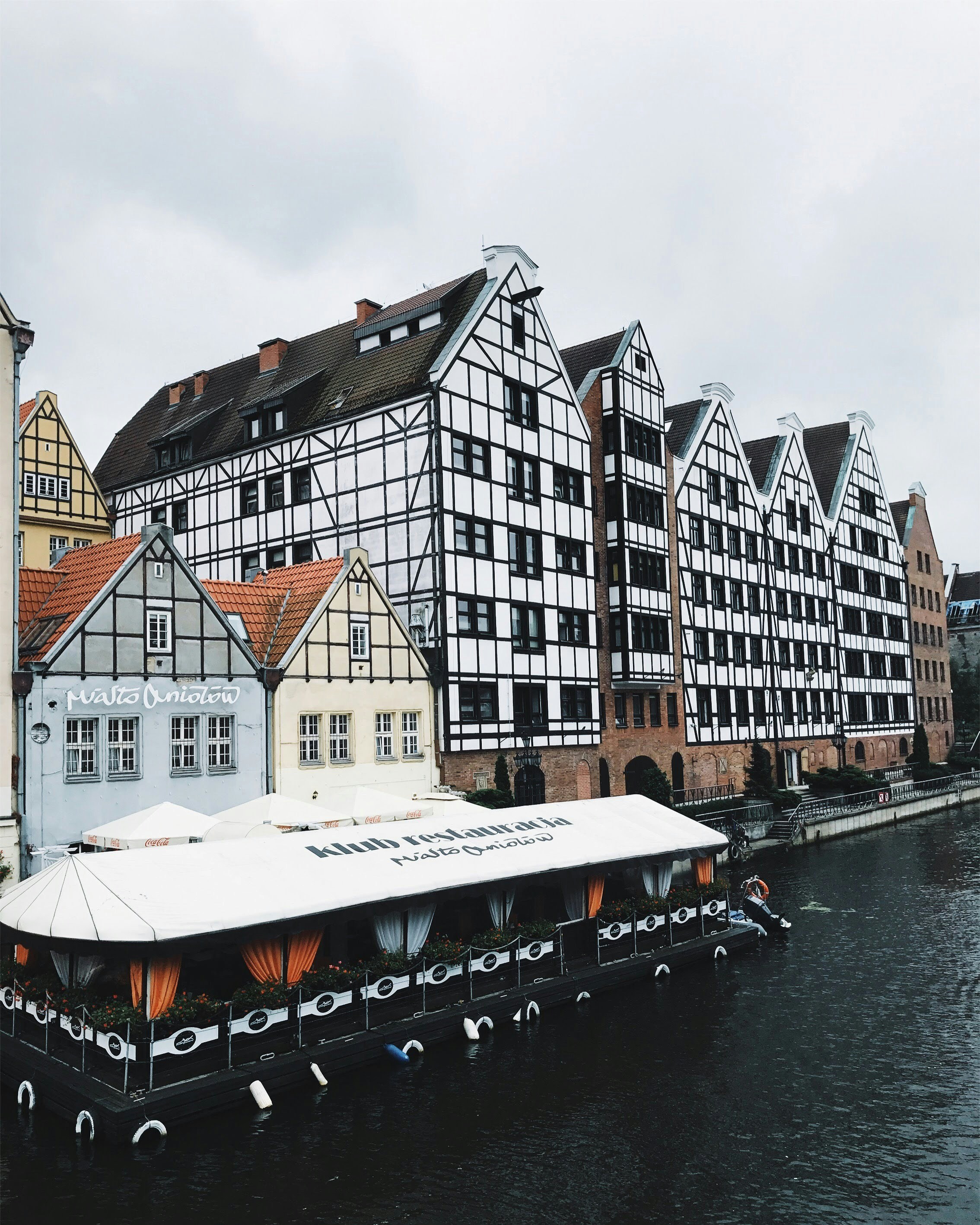A boat floating down a river next to tall buildings