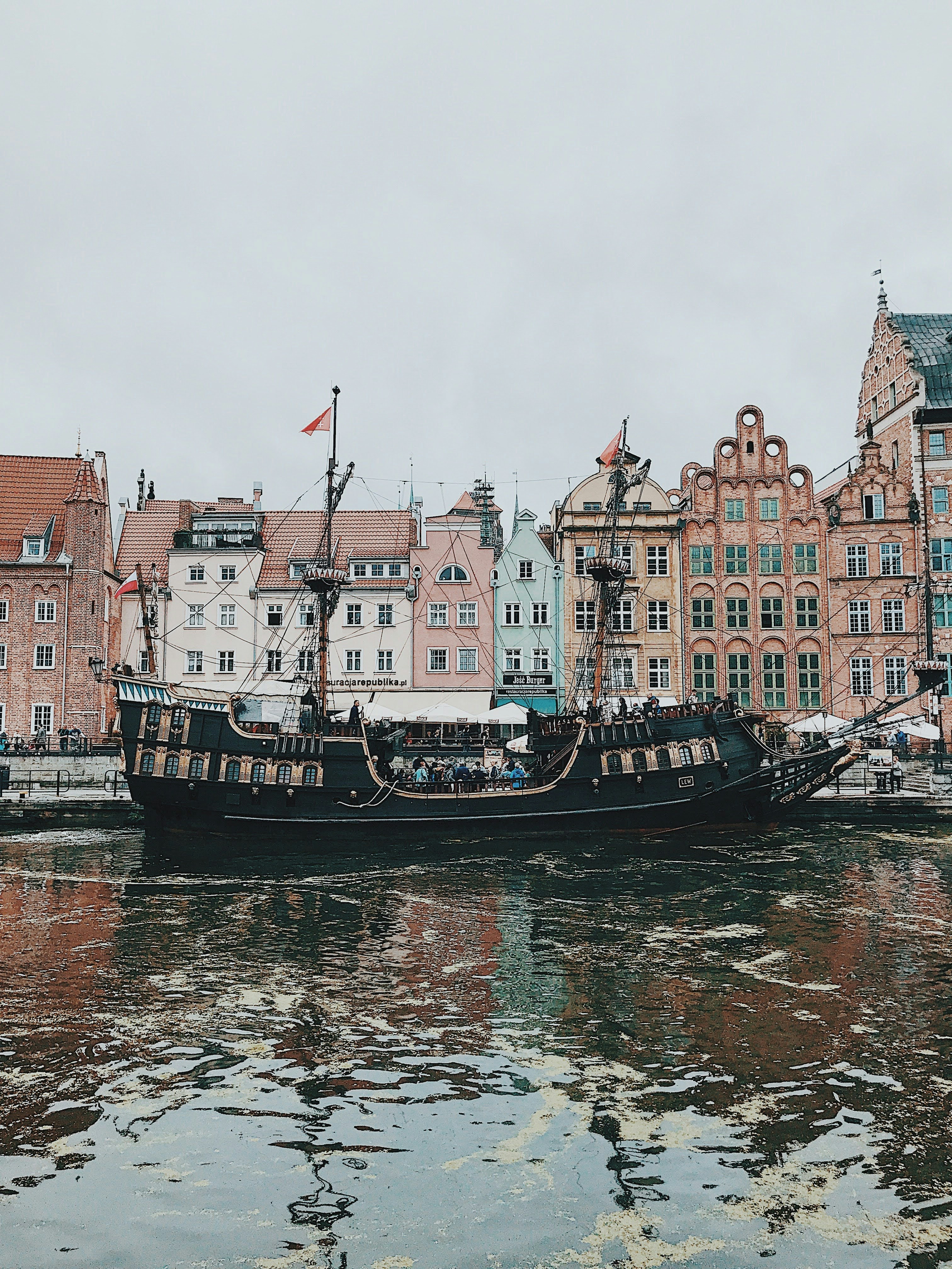 A boat floating on top of a river next to tall buildings