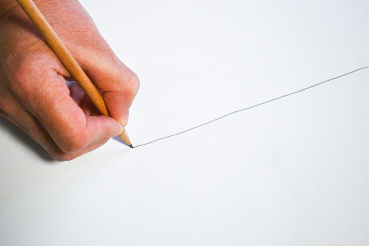 Person holding a pencil and writing on a piece of paper, intimate writing register