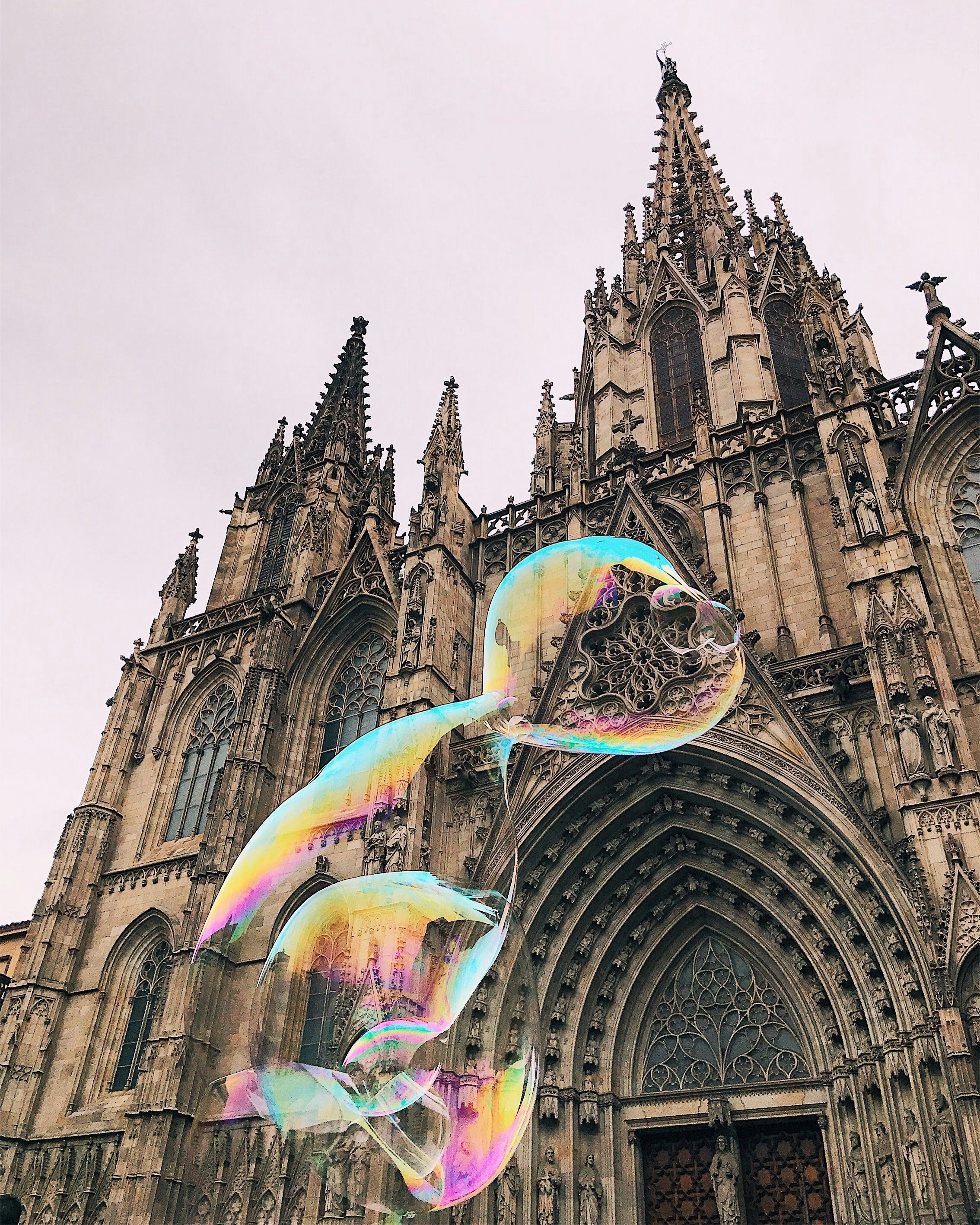 A large cathedral with a rainbow colored kite in front of it