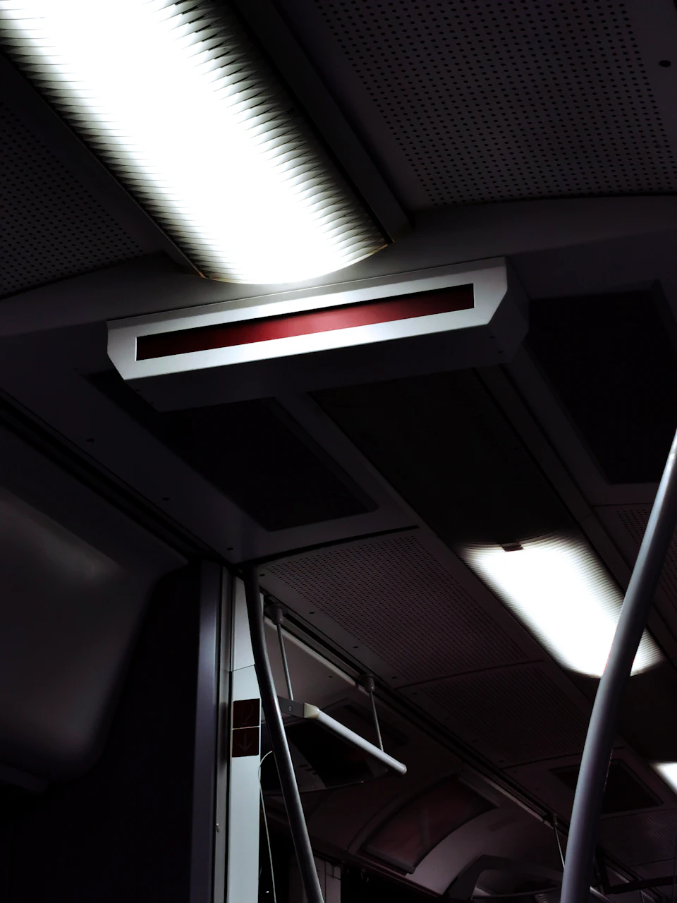 The image shows a bus interior with a large, rectangular window on the ceiling that is illuminated by two bright lights. The light source appears to be located above the window and casts a warm glow throughout the space. The bus has a gray color scheme, creating a calm atmosphere for its passengers.