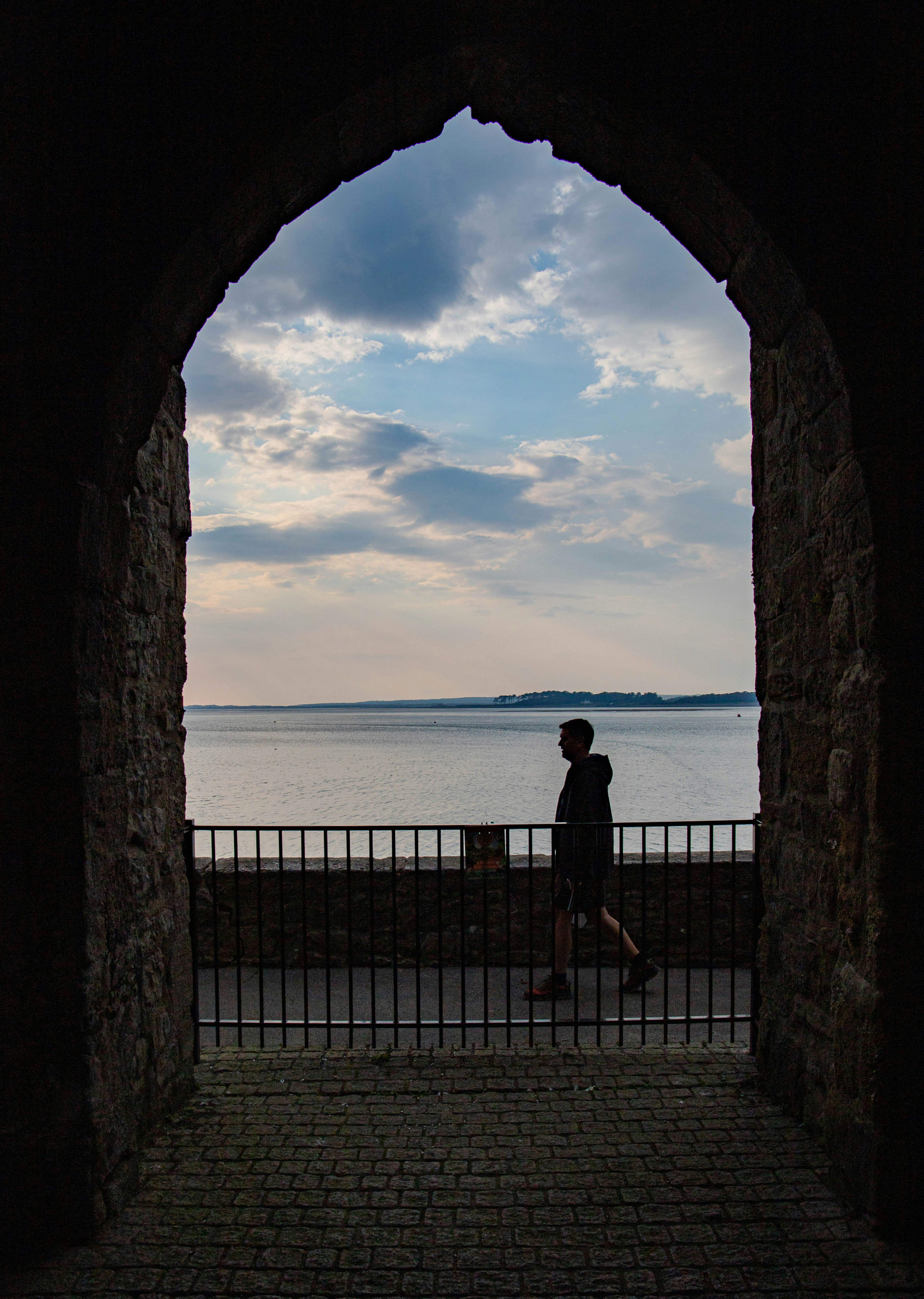 Une personne debout dans une arche regardant l’eau