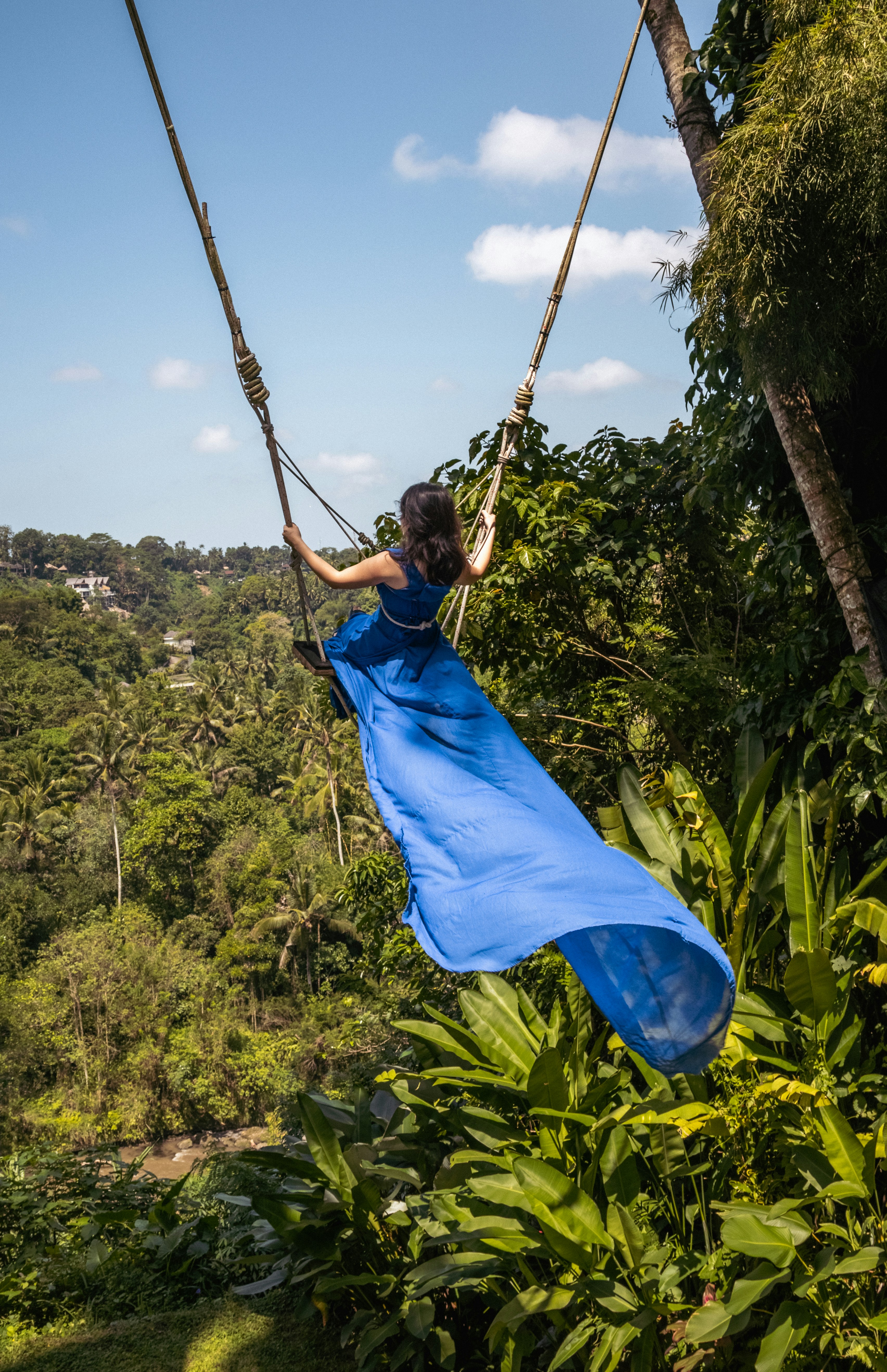 A woman in a blue dress swinging from a rope