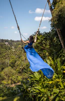 A woman in a blue dress swinging from a rope