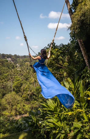 A woman in a blue dress swinging from a rope
