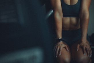 A woman sitting on a bench with her hands on her knees