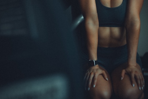 A woman sitting on a bench with her hands on her knees