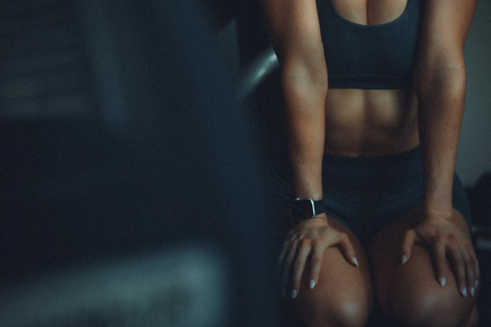 Abdomen tonificado de una mujer con ropa deportiva en luz tenue