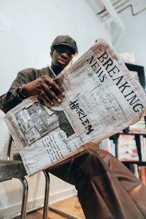 A man sitting in a chair reading a newspaper