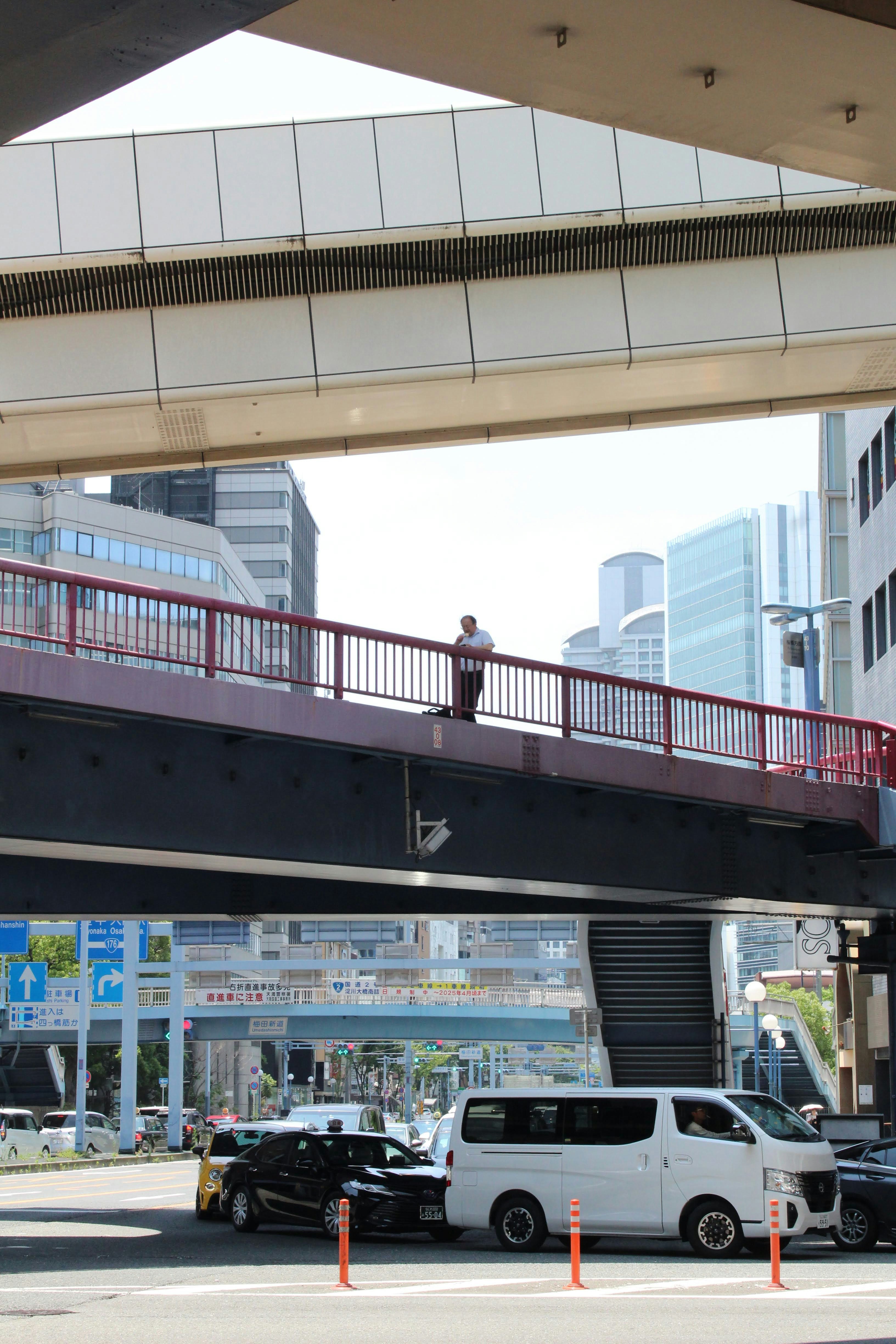 A man walking across a bridge over a street