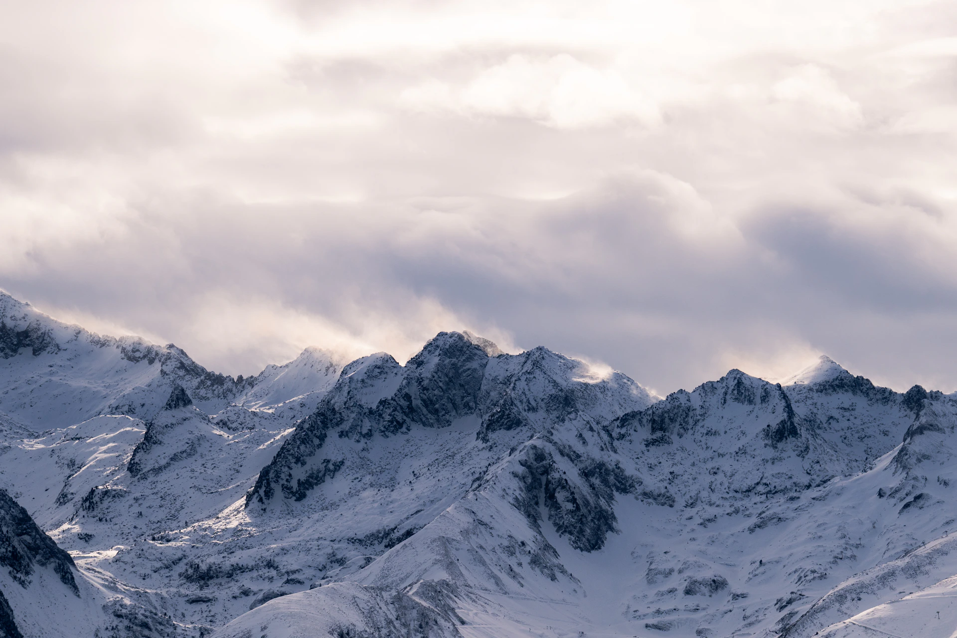 A snow covered mountain range under a cloudy sky