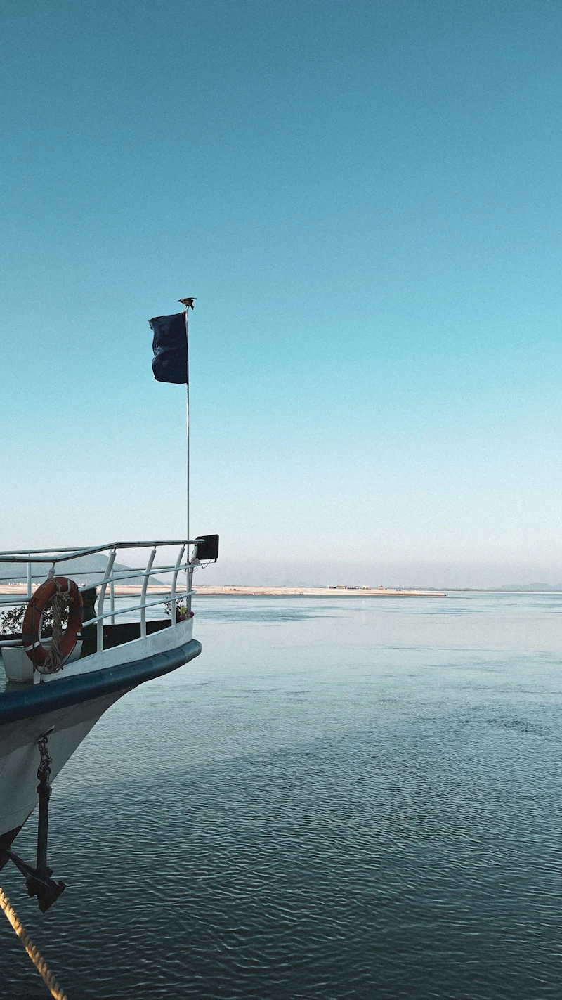 The bow of a boat on the wide, calm Brahmaputra at Guwahati under a clear sky