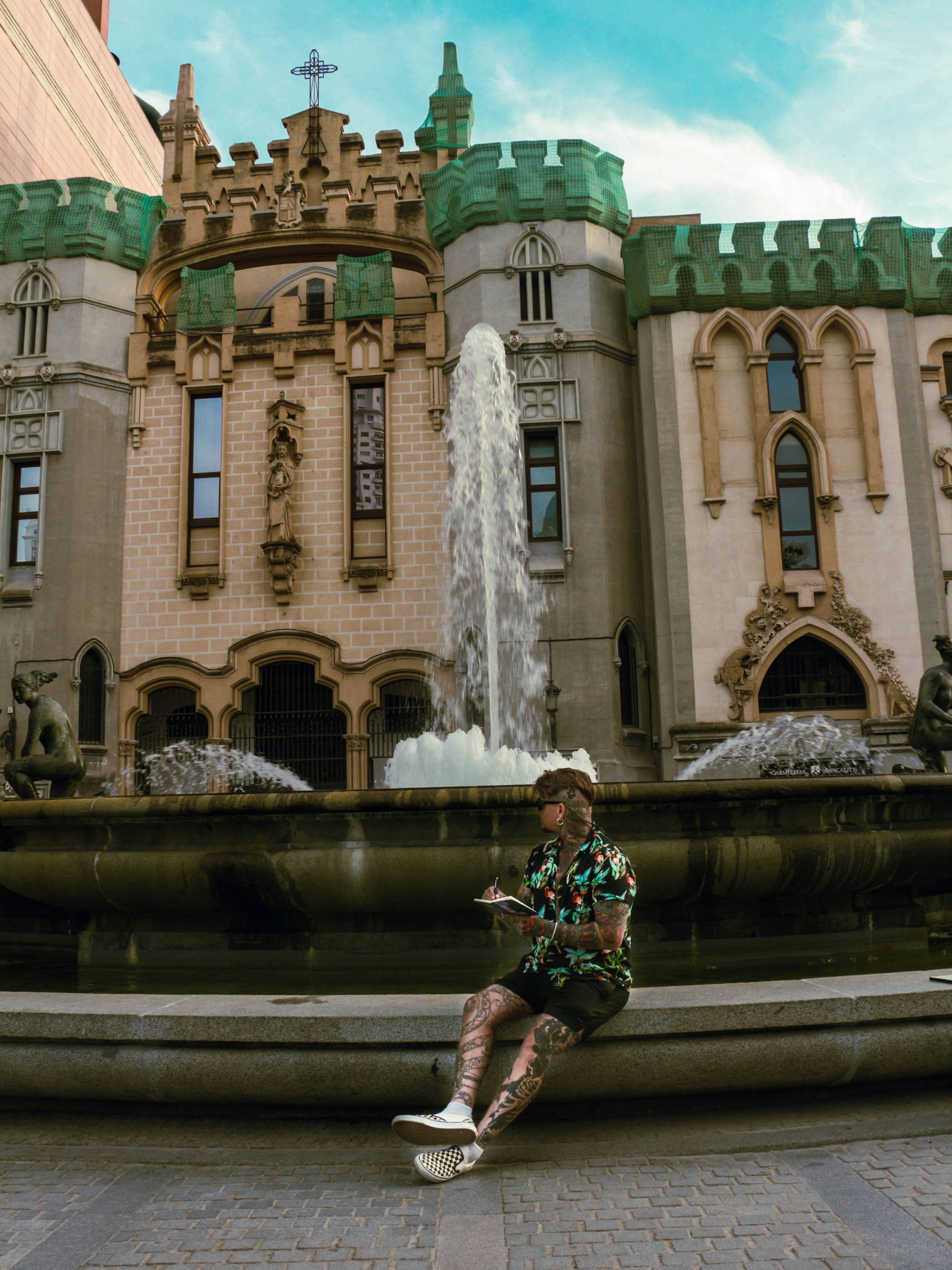 A woman sitting on a fountain in front of a building