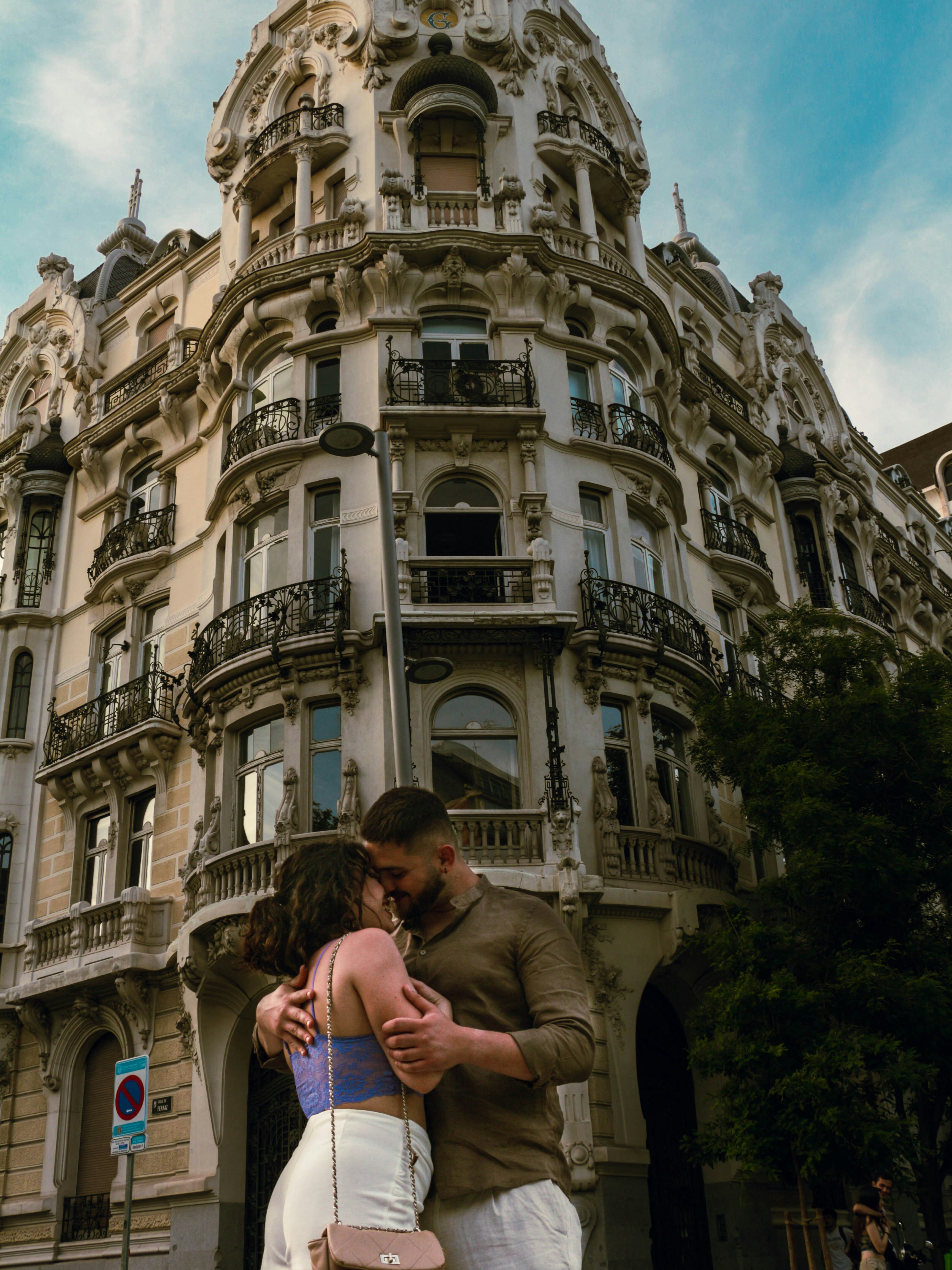 A man and a woman hugging in front of a building