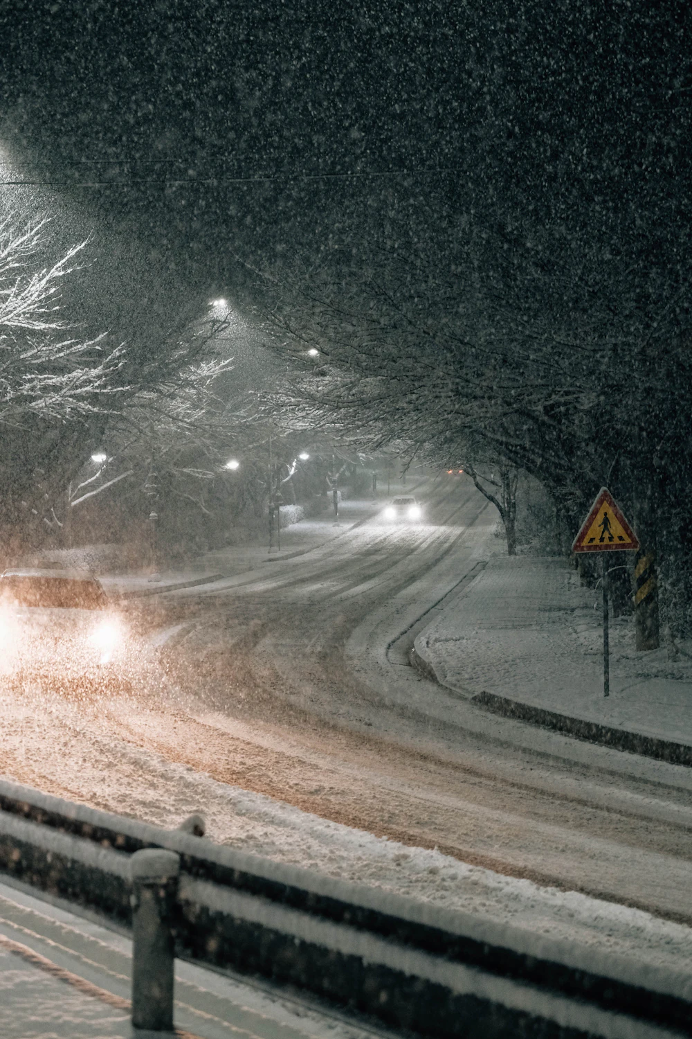 Car driving down a snowy road at night