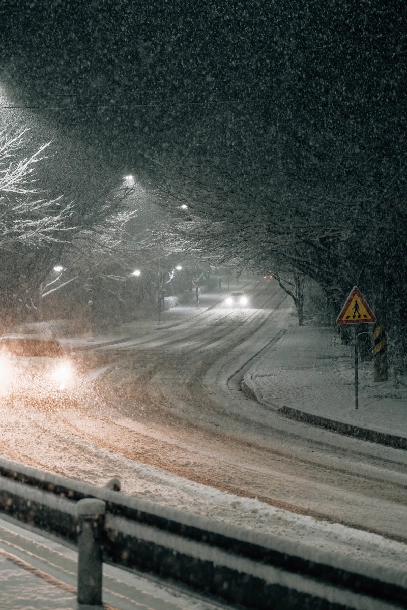 Car driving down a snowy road at night