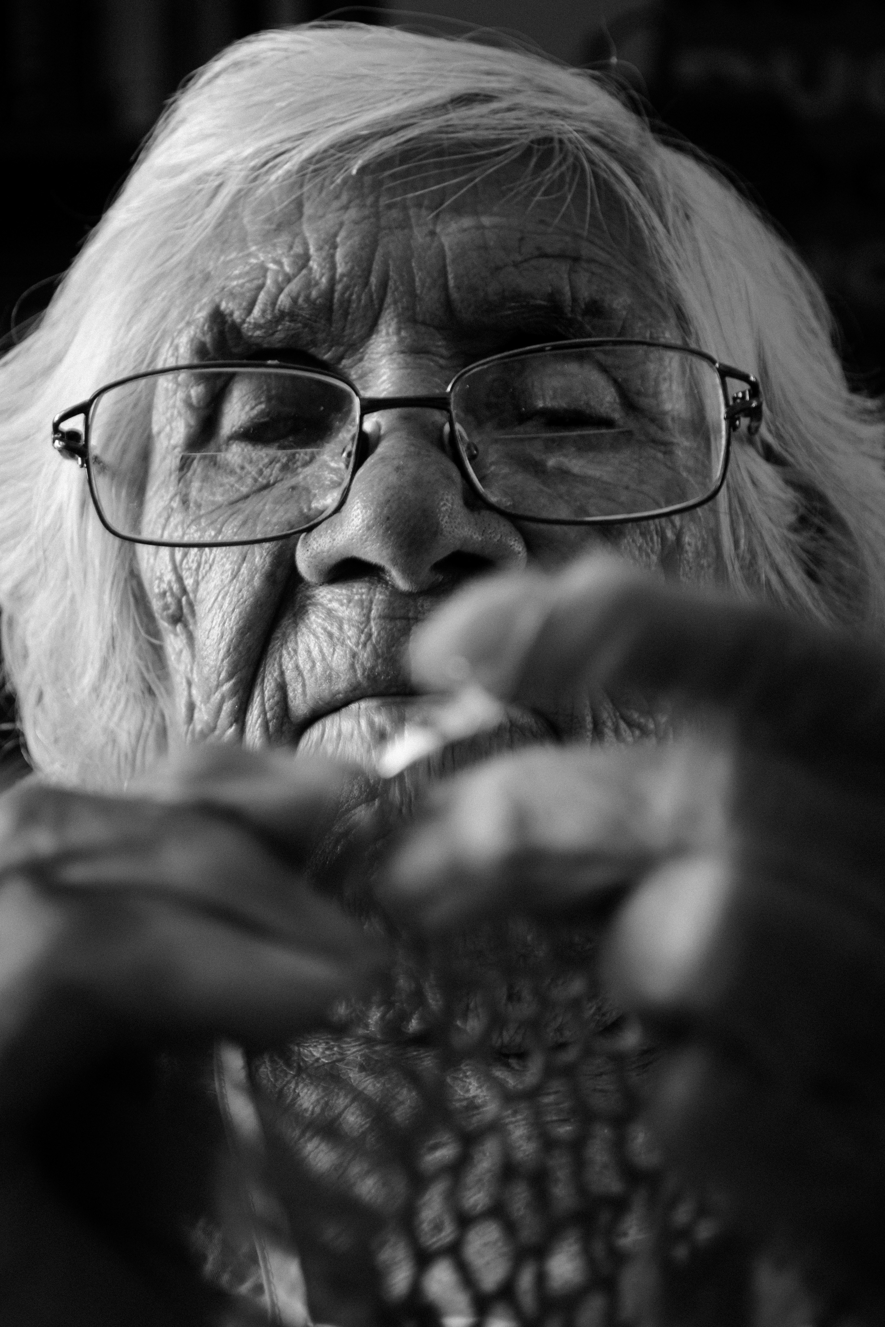 An old woman with glasses is holding something in her hands